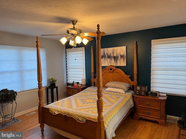 bedroom featuring multiple windows, light hardwood / wood-style floors, and ceiling fan