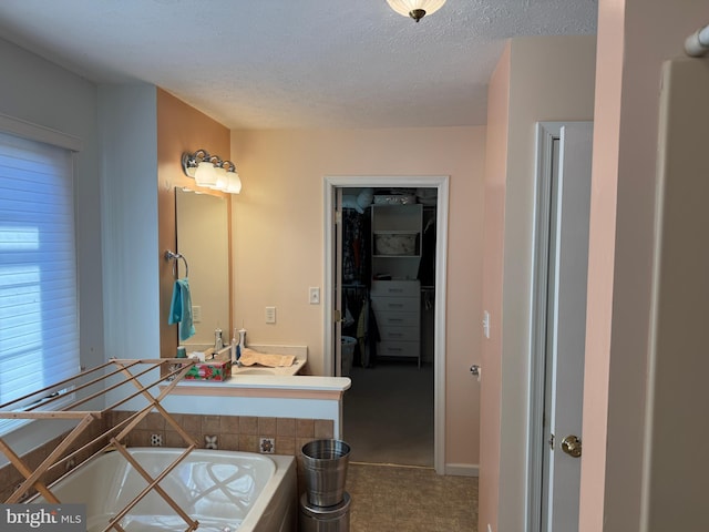 bathroom featuring a bathing tub, vanity, and a textured ceiling