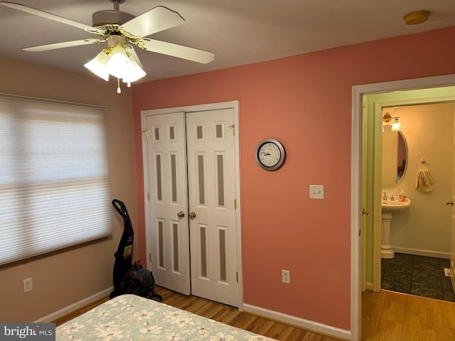 bedroom featuring ensuite bath, a closet, light hardwood / wood-style flooring, and ceiling fan