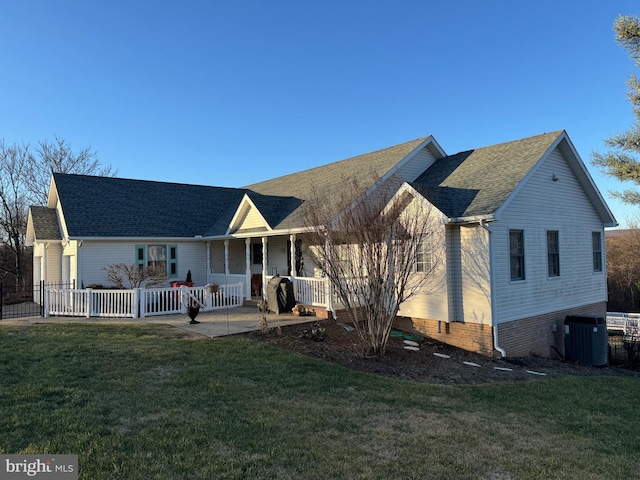 ranch-style house with a front lawn, cooling unit, and a porch