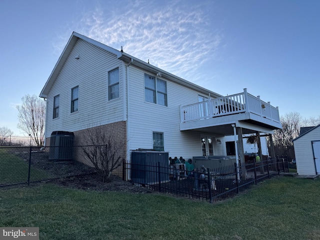 back of property featuring a deck, a yard, and a hot tub