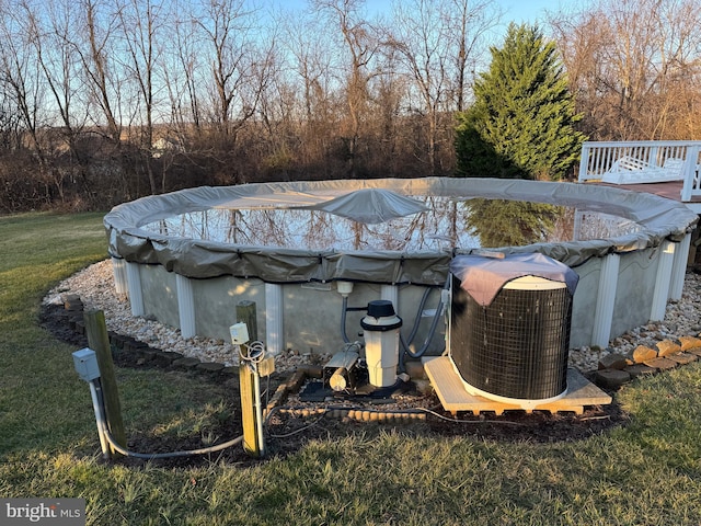 view of pool with a deck, central AC unit, and a lawn