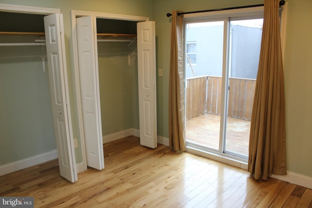 unfurnished bedroom featuring two closets and light hardwood / wood-style floors