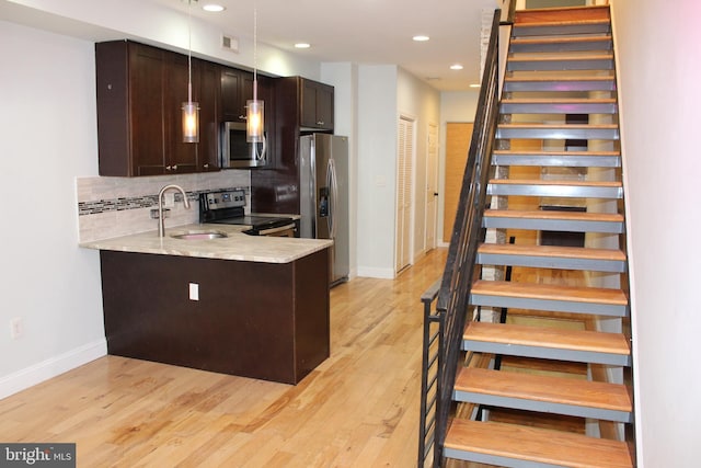 kitchen featuring sink, hanging light fixtures, dark brown cabinets, kitchen peninsula, and stainless steel appliances