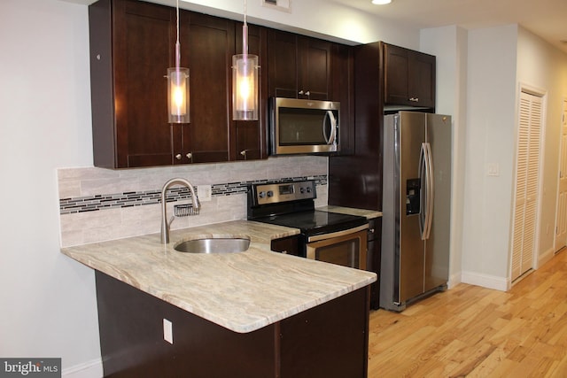 kitchen with sink, kitchen peninsula, stainless steel appliances, and hanging light fixtures