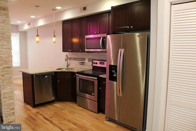 kitchen with kitchen peninsula, backsplash, stainless steel appliances, sink, and decorative light fixtures