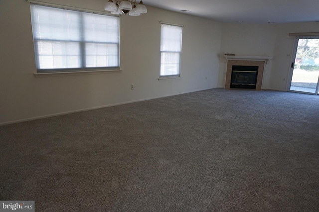 unfurnished living room with carpet flooring, a fireplace, and a chandelier