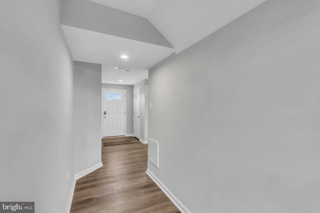 corridor with hardwood / wood-style floors and vaulted ceiling