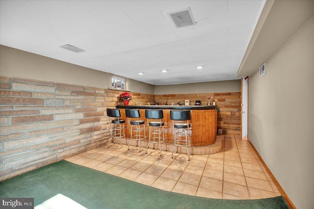 bar with light tile patterned floors and brick wall