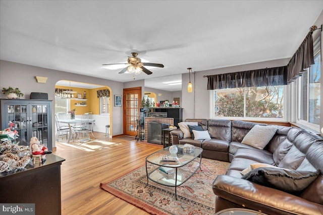 living room featuring ceiling fan with notable chandelier and light wood-type flooring