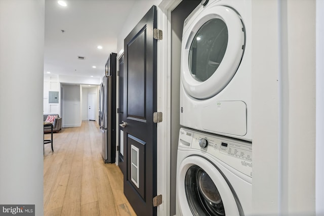 laundry area featuring stacked washer / drying machine and light hardwood / wood-style flooring