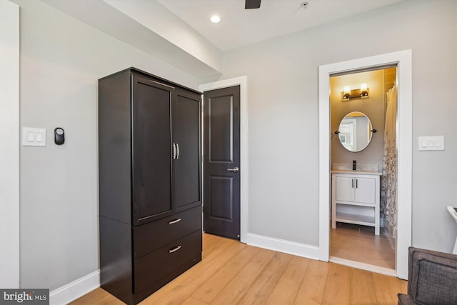 bedroom with connected bathroom, light hardwood / wood-style flooring, and sink