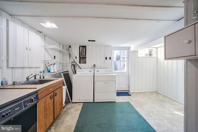 clothes washing area with washer and dryer, sink, and wooden walls