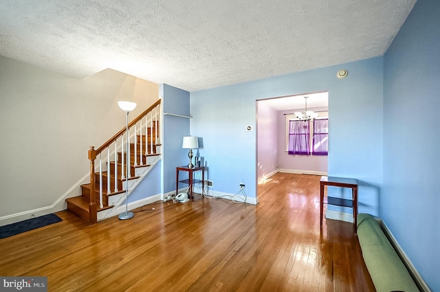 living room with hardwood / wood-style flooring, a notable chandelier, and a textured ceiling