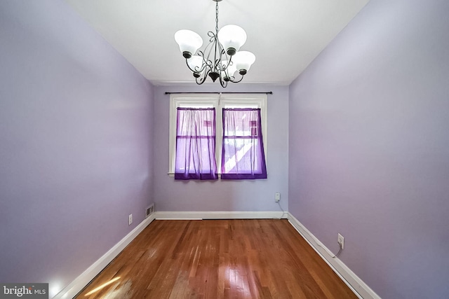 empty room featuring dark hardwood / wood-style flooring and a chandelier