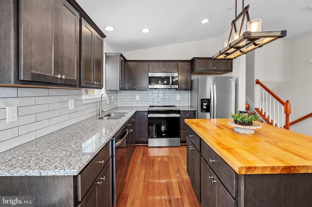 kitchen with backsplash, sink, light hardwood / wood-style flooring, appliances with stainless steel finishes, and light stone counters