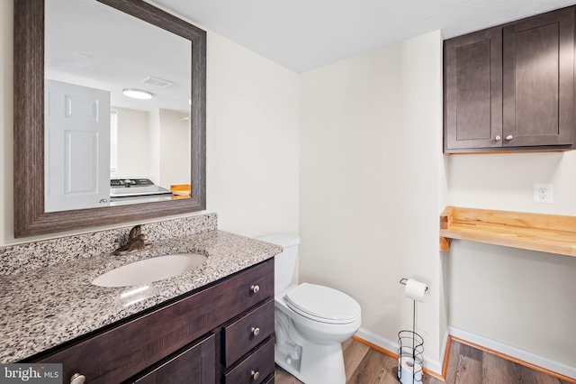 bathroom featuring toilet, hardwood / wood-style flooring, and vanity