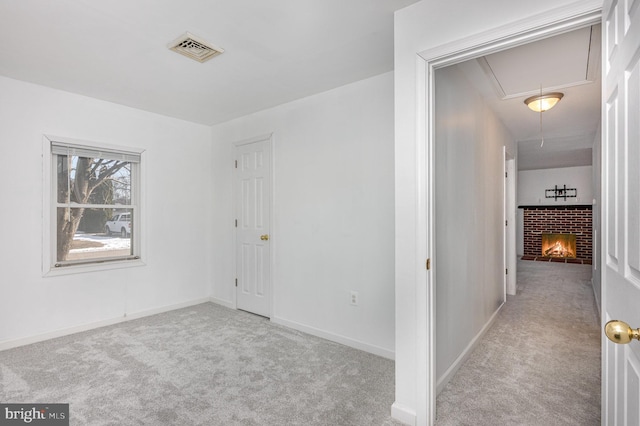 carpeted spare room featuring a brick fireplace