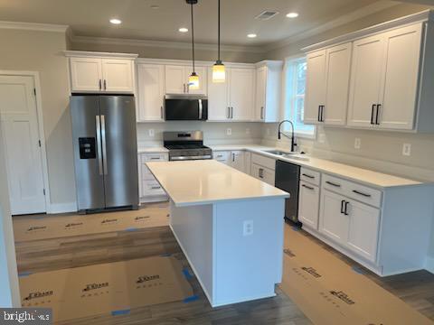 kitchen featuring white cabinets, stainless steel appliances, a sink, and hanging light fixtures