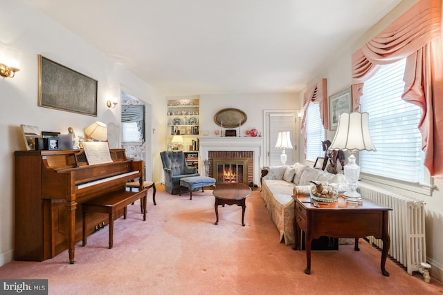 living area featuring built in features, carpet, radiator heating unit, and a fireplace