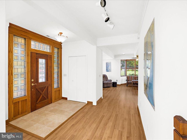 entryway featuring wood-type flooring, track lighting, and ornamental molding