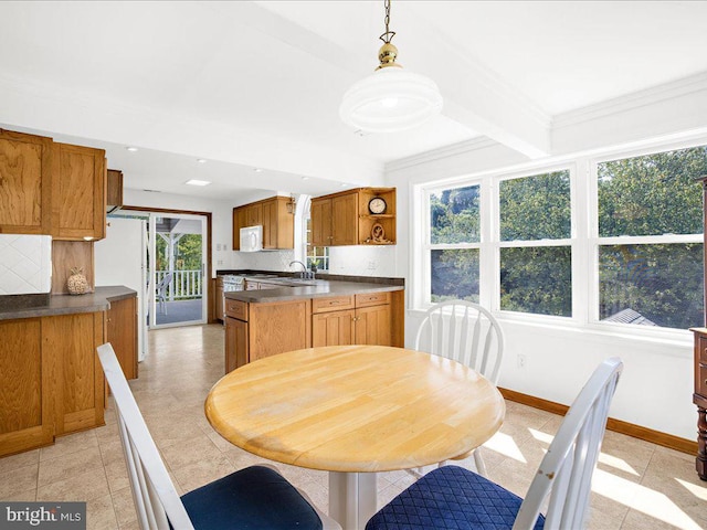 dining area featuring beam ceiling, sink, light tile patterned floors, and a healthy amount of sunlight