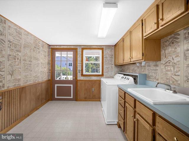 washroom featuring washer and clothes dryer, wood walls, sink, and cabinets