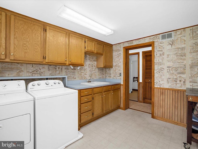 washroom featuring wooden walls, sink, cabinets, and independent washer and dryer