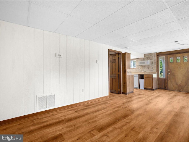 unfurnished living room with light hardwood / wood-style flooring and wood walls