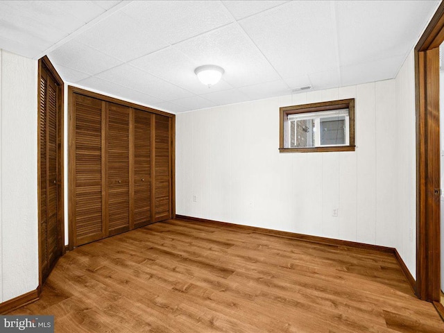 unfurnished bedroom featuring a paneled ceiling, a closet, and hardwood / wood-style flooring