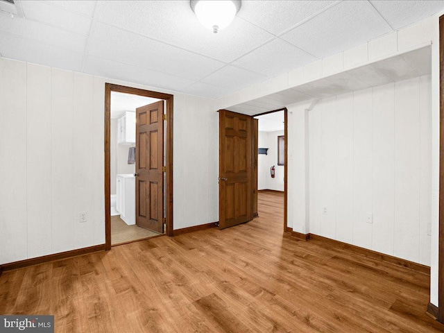 unfurnished bedroom featuring a paneled ceiling, light hardwood / wood-style floors, and connected bathroom