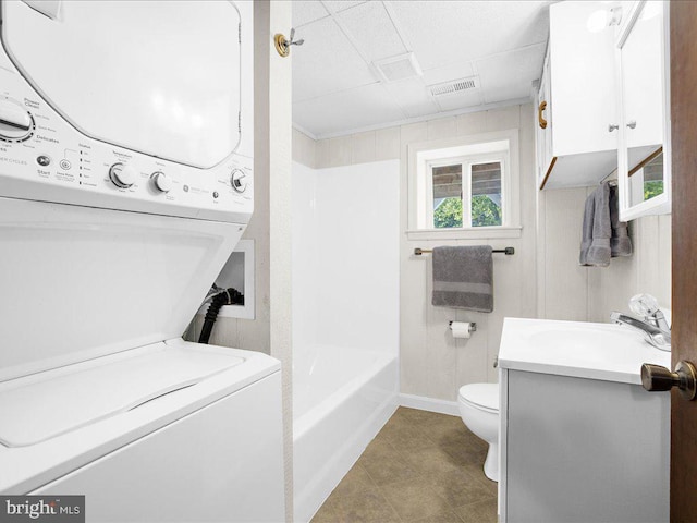 interior space featuring stacked washer / drying machine, toilet, and vanity