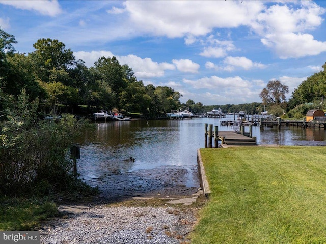 view of dock featuring a lawn and a water view