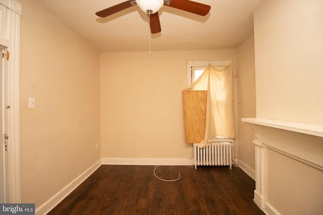 empty room featuring radiator heating unit, dark hardwood / wood-style floors, and ceiling fan