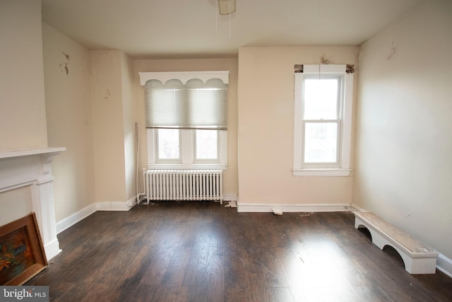 unfurnished living room with dark hardwood / wood-style floors and radiator heating unit