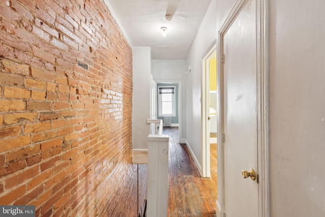 hall featuring hardwood / wood-style flooring and brick wall