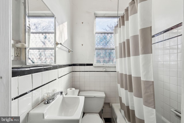 full bathroom featuring sink, a healthy amount of sunlight, tile walls, and toilet