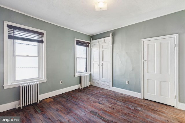 unfurnished bedroom featuring dark hardwood / wood-style floors and radiator