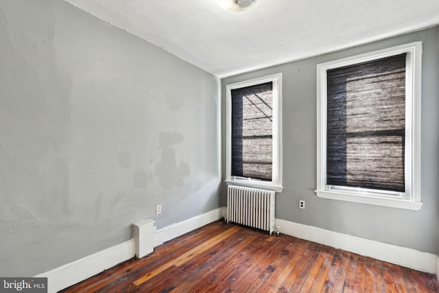 spare room with radiator heating unit, a textured ceiling, and dark hardwood / wood-style floors