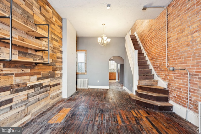 entrance foyer featuring a high ceiling, an inviting chandelier, dark hardwood / wood-style floors, radiator heating unit, and brick wall