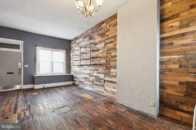 entryway featuring a chandelier, dark wood-type flooring, and a textured ceiling