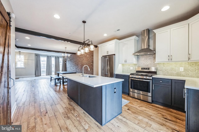 kitchen with white cabinets, appliances with stainless steel finishes, wall chimney exhaust hood, decorative light fixtures, and beamed ceiling