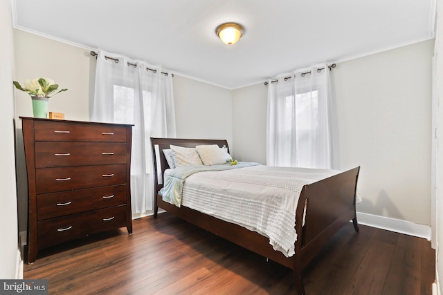 bedroom featuring crown molding, dark wood finished floors, and baseboards