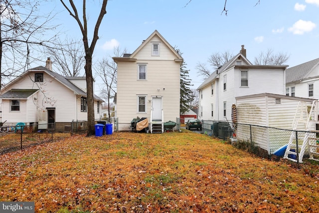 rear view of property featuring entry steps, a yard, cooling unit, and a fenced backyard