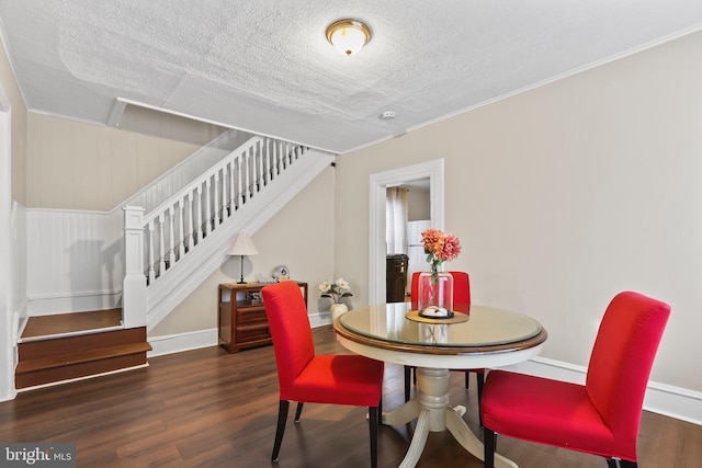 dining space featuring a textured ceiling, stairs, baseboards, and wood finished floors