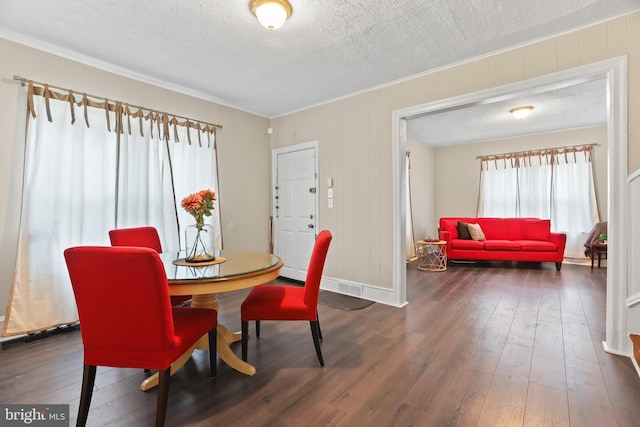 dining area with crown molding, a textured ceiling, baseboards, and dark wood-style flooring