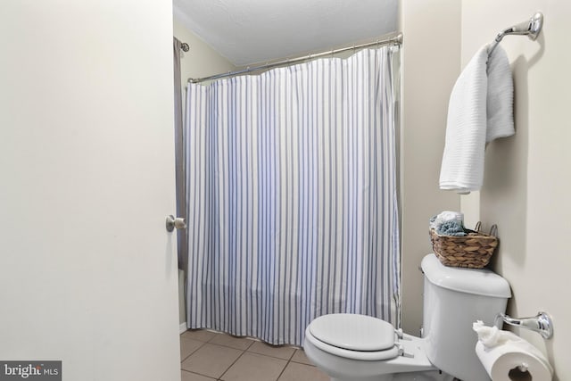 bathroom with a textured ceiling, tile patterned flooring, toilet, and a shower with curtain