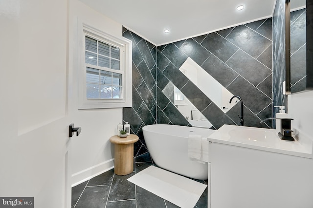 bathroom featuring tile patterned flooring, vanity, a bathtub, and tile walls