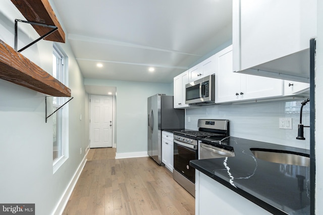 kitchen featuring sink, stainless steel appliances, light hardwood / wood-style flooring, backsplash, and white cabinets