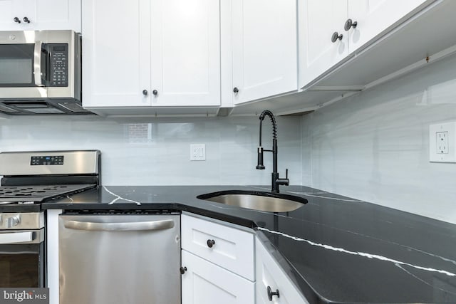 kitchen featuring decorative backsplash, stainless steel appliances, white cabinetry, and sink